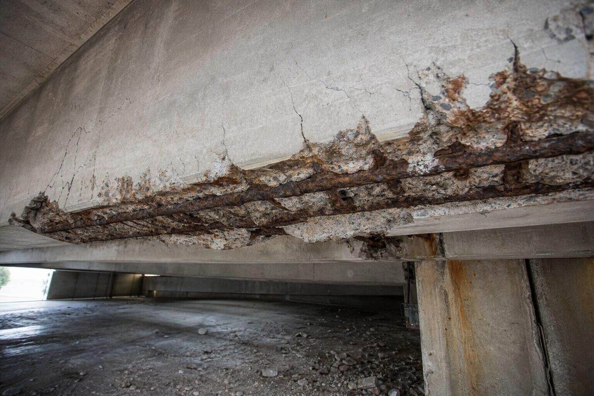 Concrete spalling with exposed corroded reinforcement on a carpark beam soffit